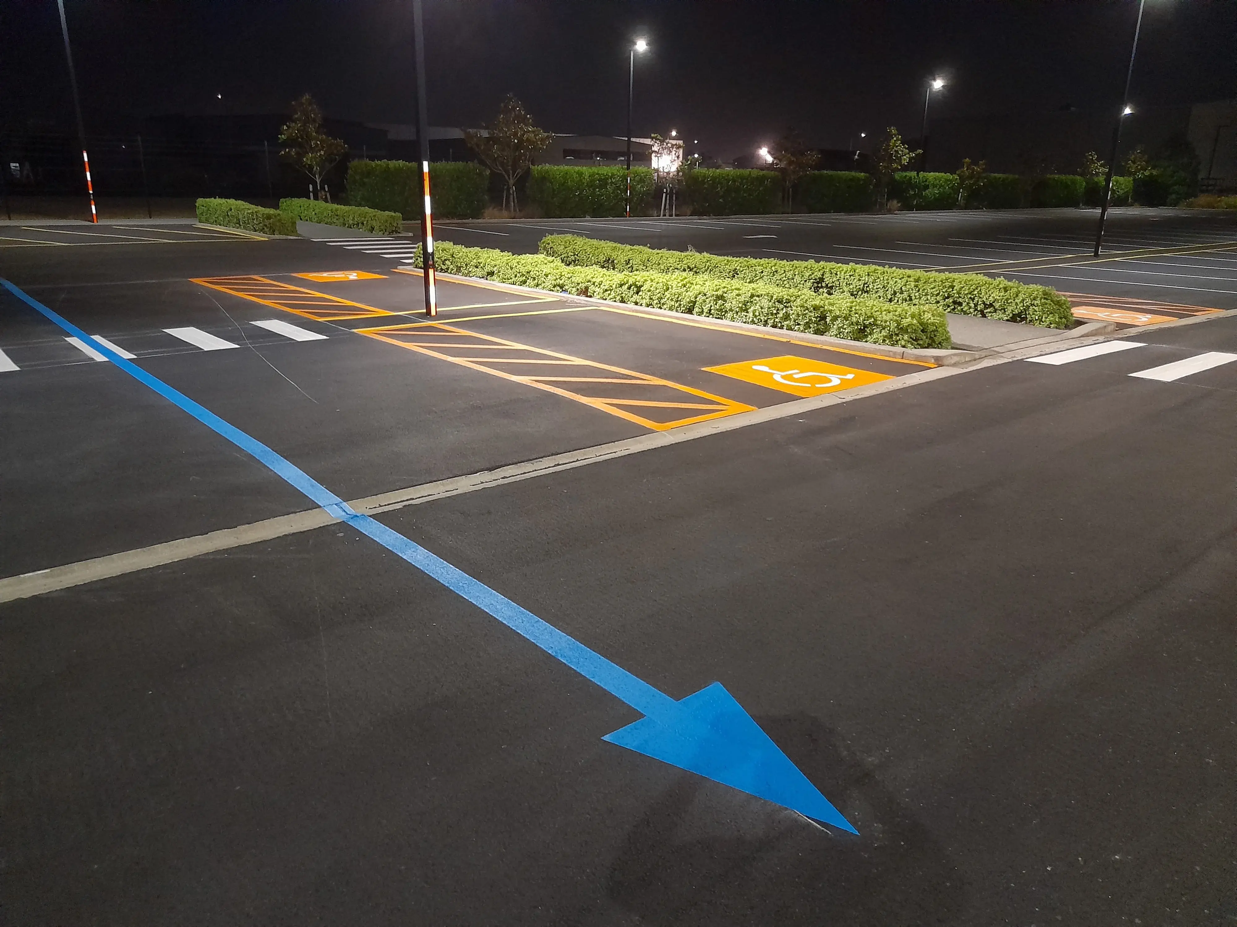 Directional arrows, mobility bays and disability symbols marked at a commercial car park.