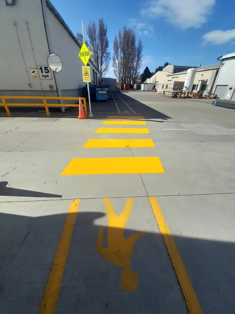 Yellow pedestrian crossing and directional arrow markings in a Christchurch commercial car park