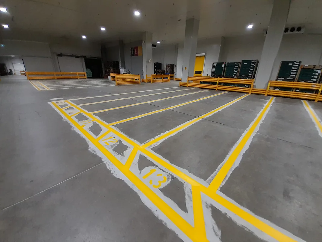 Fresh yellow bay numbers and safety lanes for a warehouse distribution floor.