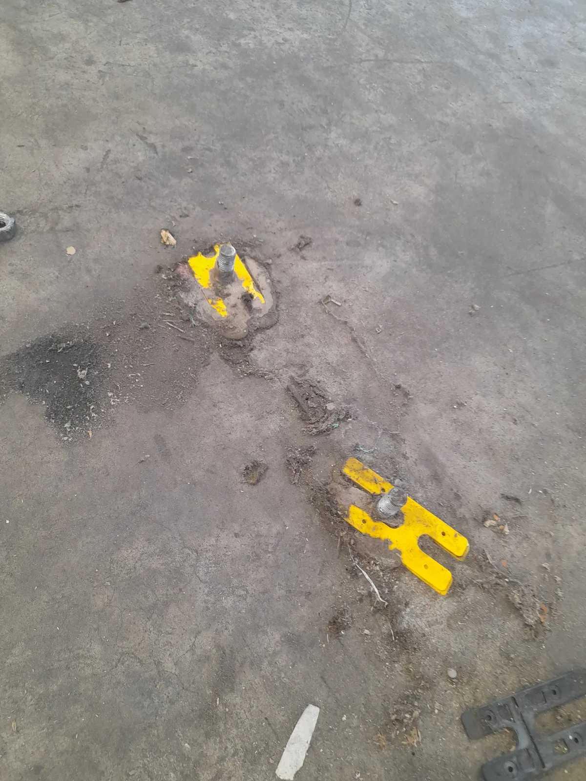 Protruding racking anchor bolts with yellow base plates on warehouse concrete floor before make-good — Christchurch