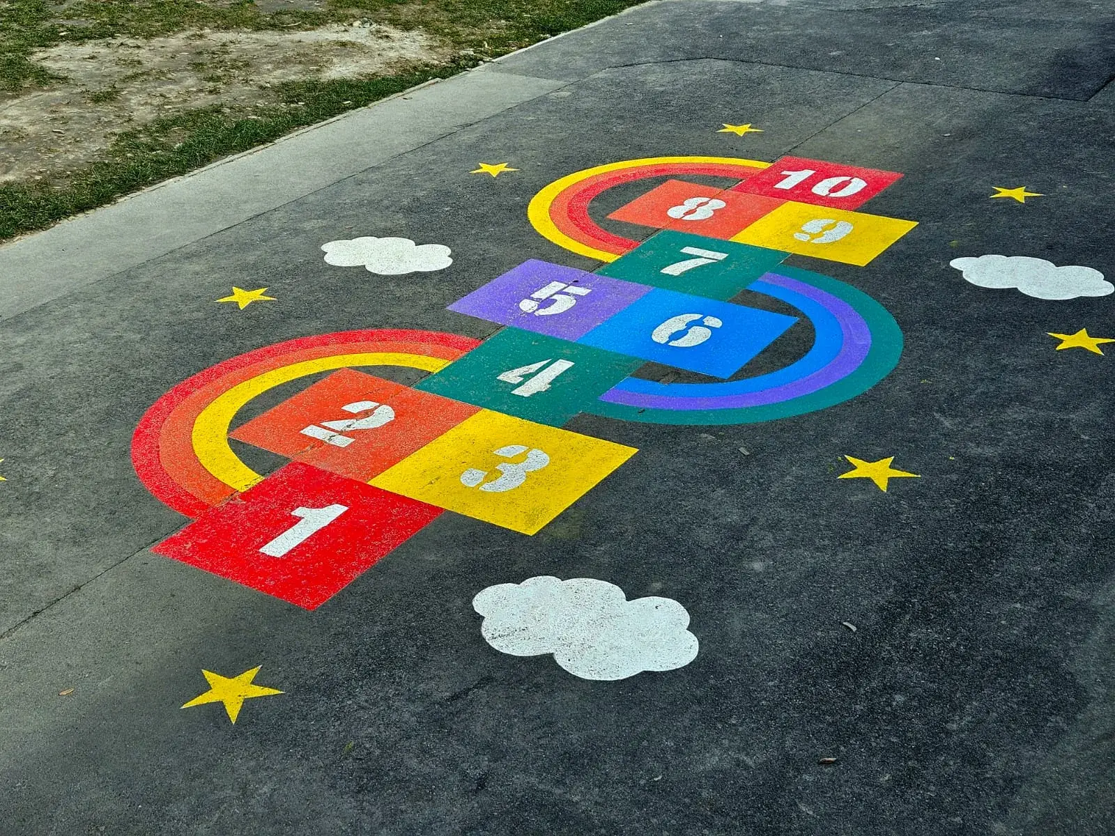 Rainbow hopscotch with clouds and stars painted on school playground