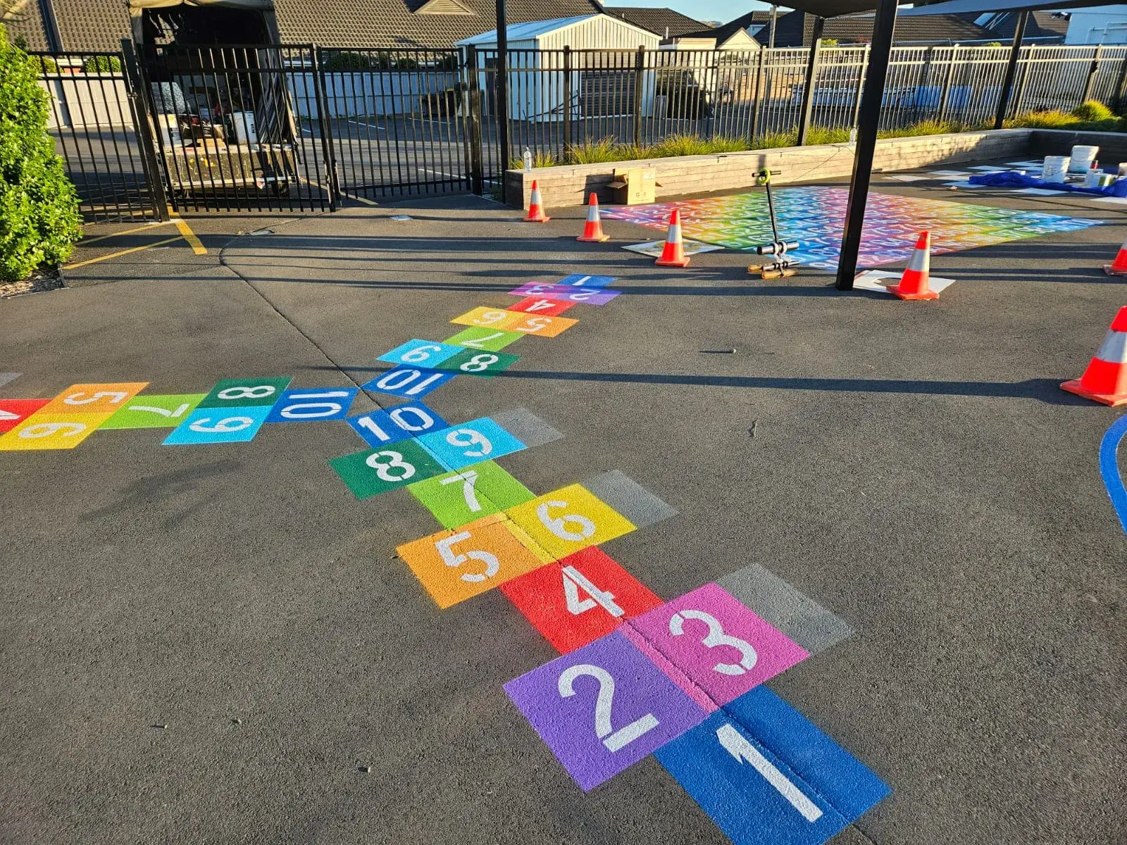 Colourful snakes and ladders hopscotch painted on school playground with number grid in background