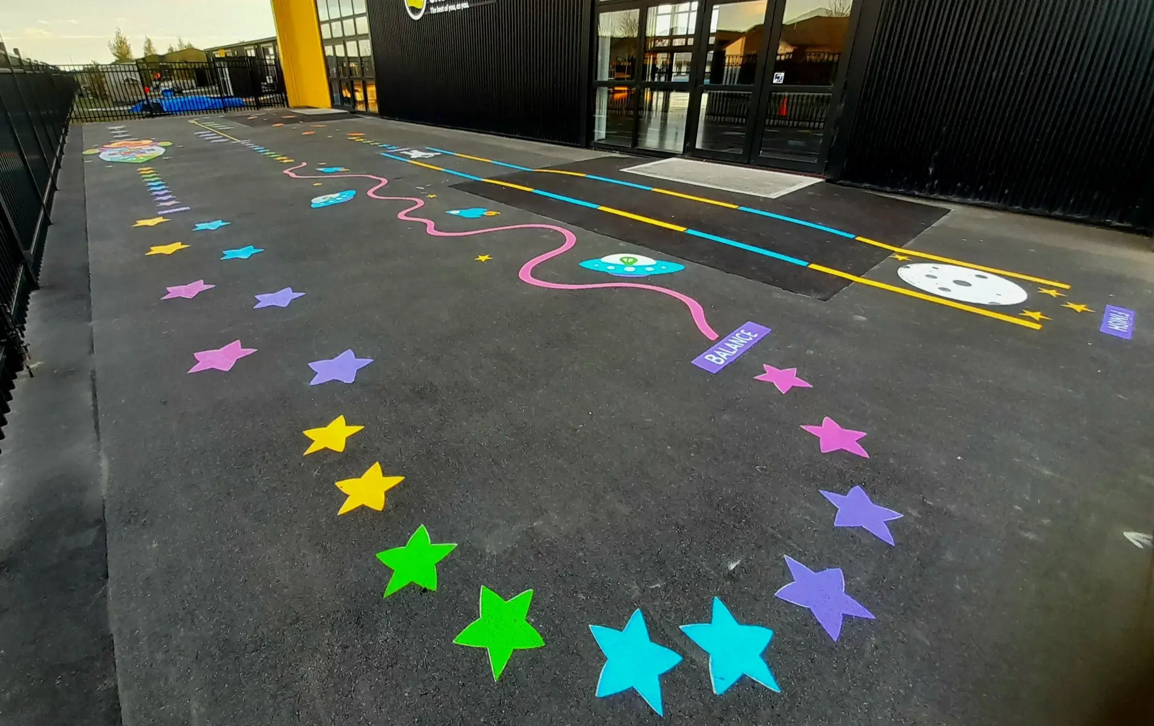 Painted space track with colourful stars, aliens, and balance trail on school playground