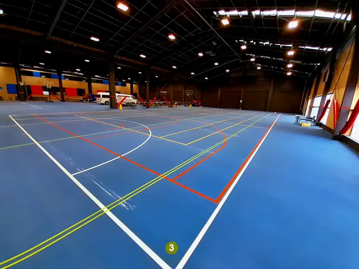 Multi-sport indoor court with coloured line marking on blue floor