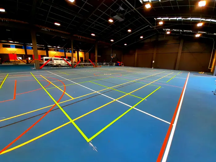 Large indoor sports complex with multi-sport line marking on blue surface
