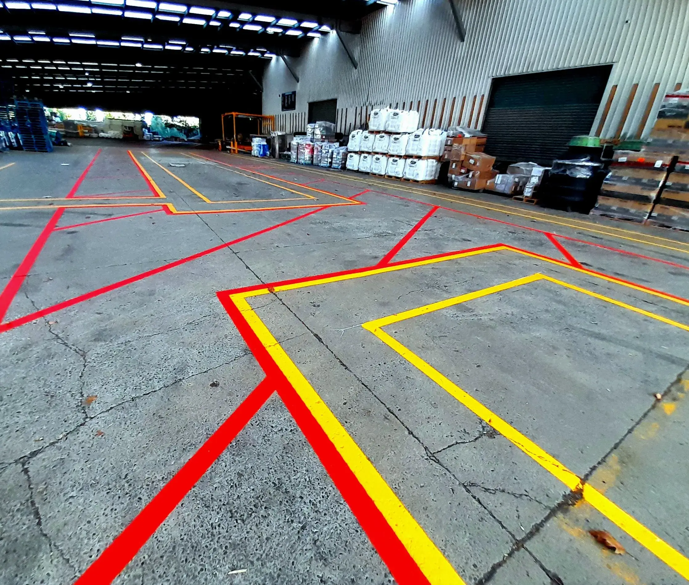 Ground-level view of red and yellow floor markings at warehouse entrance